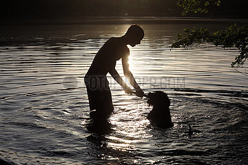 Dranse  Deutschland  Silhouette: Jugendlicher und Hund spielen in einem See miteinander
