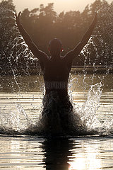 Dranse  Deutschland  Silhouette: Jugendlicher springt am Abend beim Baden aus einem See heraus