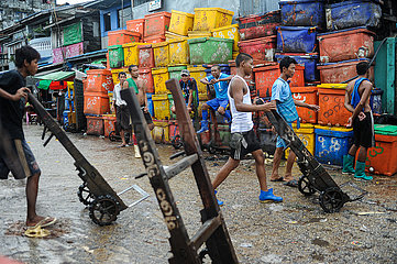 Yangon  Myanmar  Arbeiter mit Sackkarren vor bunten Kuehlboxen auf dem traditionellen Baho San Pya Fischmarkt