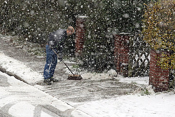 Berlin  Deutschland  Mann beseitigt vor seinem Grundstueck den frisch gefallenen Schnee vom Gehweg