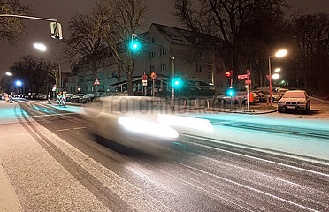 Berlin  Deutschland  Dynamik: Auto faehrt in der Nacht auf einer mit Schnee bedeckten Strasse