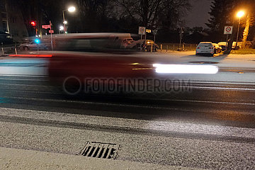 Berlin  Deutschland  Dynamik: Auto faehrt in der Nacht auf einer mit Schnee bedeckten Strasse