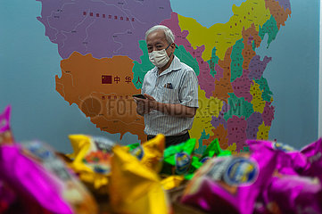 Singapur  Republik Singapur  Mann mit Mundschutz vor einer Landkarte in Chinatown waehrend der Corona-Pandemie