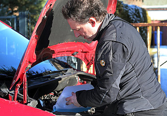 Neuenhagen  Deutschland  Mann fuellt Frostschutzmittel in das Scheibenwischsystem seines Autos