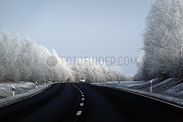 Bruchmuehle  Deutschland  Auto faehrt im Winter auf einer Landstrasse an mit Raureif behafteten Baeumen vorbei