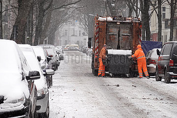 Berlin  Deutschland  Mitarbeiter der BSR schieben bei Schneefall eine volle Restmuelltonne zur Entleerung an den Muellwagen
