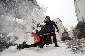 Berlin  Deutschland  Mann schaufelt vor seinem Grundstueck den frisch gefallenen Schnee vom Gehweg