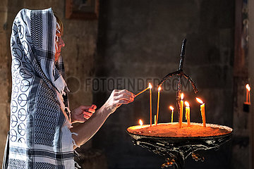 Tiflis  Georgien  mit Kopftuch verhuellte Touristin zuendet in einer Kirche eine Kerze an