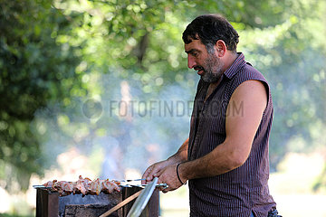 Keda  Georgien  Mann grillt in einem Park Fleischspiesse auf einem Holzkohlengrill