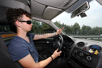 Kufstein  Oesterreich  junger Mann zeigt beim Autofahren den Mittelfinger