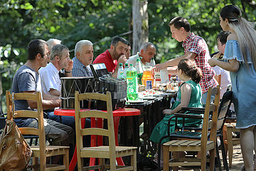 Keda  Georgien  Maenner und Kinder essen gemeinsam im Freien an einem Tisch