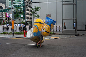 Singapur  Republik Singapur  Mann geht eine Strasse im Stadtzentrum entlang und traegt Minions-Kostueme