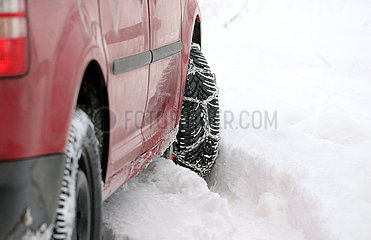 Graditz  Deutschland  Auto mit aufgezogener Schneekette faehrt durch tiefen Schnee