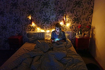 Dranse  Deutschland  Frau sitzt nachts im Bett und schaut ihr Smartphone