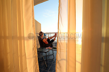 Batumi  Georgien  Frau sitzt auf dem Balkon eines Hotels und schaut auf ihr Smartphone