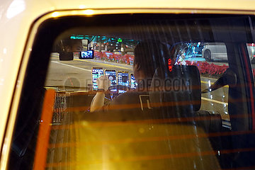 Hong Kong  China  Taxifahrer schaut waehrend der Fahrt auf eines seiner zahlreichen Smartphones