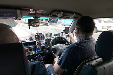 Hong Kong  China  Taxifahrer schaut waehrend der Fahrt auf ein Smartphone