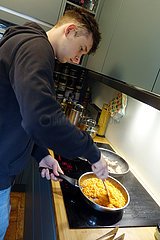Berlin  Deutschland  junger Mann beim Kochen