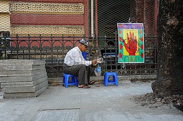 Yangon  Myanmar  Ein Handleser sitzt in der ehemaligen Hauptstadt auf einem Plastikhocker