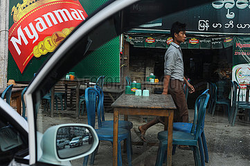 Yangon  Myanmar  Ein Mann geht an leeren Tischen eines Restaurants am Strassenrand vorbei