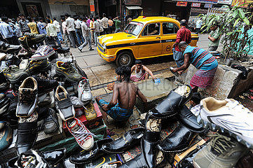 Kalkutta  Indien  Maenner waschen sich an einem kommunalen Waschplatz auf der Strasse waehrend ein Taxi vorbeifaehrt