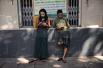Yangon  Myanmar  Zwei junge Maenner surfen auf ihren Handys im Internet