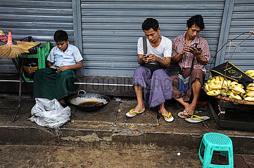 Yangon  Myanmar  Drei junge Menschen surfen auf ihren Handys im Internet