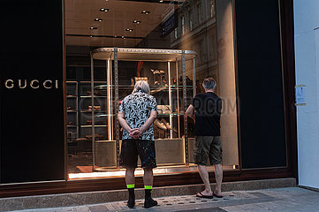 Wien  Oesterreich  Maenner stehen vorm Schaufenster eines Geschaefts von Gucci in einer Fussgaengerzone