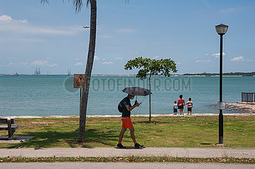 Singapur  Republik Singapur  Mann geht am Ufer des Changi Beach Parks entlang waehrend sich ein Flugzeug naehert