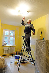 Berlin  Deutschland  Mann streicht in seiner Wohnung die Kuechendecke