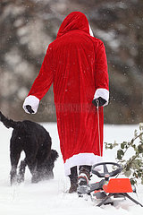 Berlin  Deutschland  Weihnachtsmann zieht in Begleitung eines Hundes seinen Schlitten hinter sich her