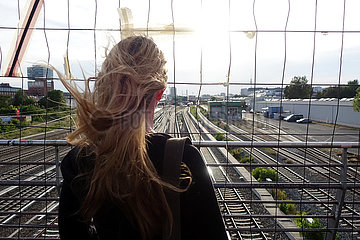 Berlin  Deutschland  Frau schaut durch ein Gitter auf Bahngleise