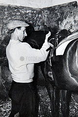 Hannover  Stallmeister Hans Krueger sattelt ein Pferd in der Box