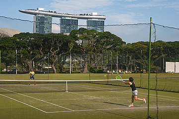Singapur  Republik Singapur  Zwei Spieler spielen Tennis mit dem Marina Bay Sands Hotel im Hintergrund