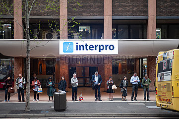 Sydney  Australien  Menschen starren aufs Handy waehrend sie nach Feierabend an einer Bushaltestelle warten