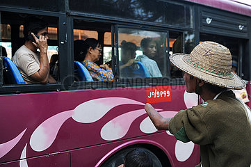 Yangon  Myanmar  Mann ohne Unterarm bettelt Fahrgaeste eines Busses an
