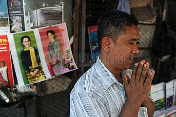 Yangon  Myanmar  Strassenhaendler betet an seinem Strassenstand