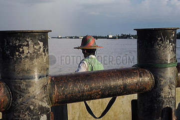 Yangon  Myanmar  Flusstaxifahrer wartet an Anlegestelle am Ufer des Yangon River zwischen rostigen Pollern