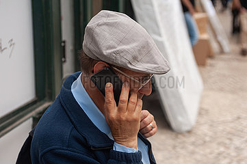 Lissabon  Portugal  Aelterer Mann mit Schiebermuetze telefoniert auf seinem Handy