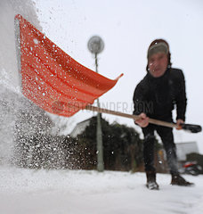 Berlin  Deutschland  Mann schaufelt frisch gefallenen Schnee vom Gehweg