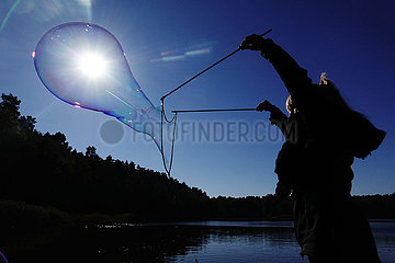 Dranse  Deutschland  Silhouette: Frau macht an einem See mit einem Seil eine grosse Seifenblase