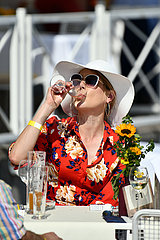 Iffezheim  Deutschland  elegant gekleidete Frau mit Hut trinkt aus einem Glas
