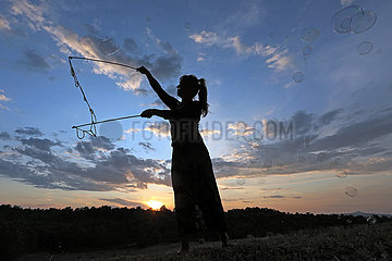 Capodimonte  Italien  Silhouette: Frau macht bei Daemmerung mit einem Seil grosse Seifenblasen