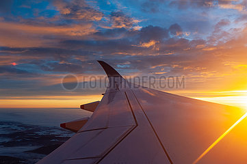 Schweiz  Luftbild im Flug nach Zuerich waehrend Sonnenaufgang mit Blick aus Flugzeug auf Fluegel und rotem Himmel