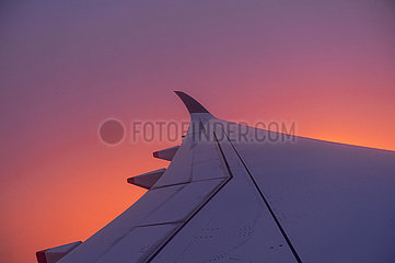 Schweiz  Luftbild im Flug nach Zuerich waehrend Sonnenaufgang mit Blick aus Flugzeug auf Fluegel und rotem Himmel