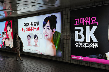 Seoul  Suedkorea  Reklameschilder werben in der Unterfuehrung einer U-Bahnstation fuer Schoenheitsoperationen