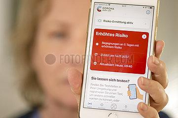 Frau  Ü60  zeigt Corona Warn App auf ihrem Smartphone  Warnstufe Rot  5 Risikobegegnungen in den letzten Tagen  München  Januar 2022
