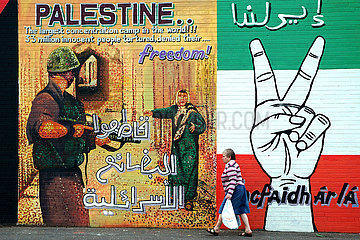 Nordirland. Ulster. Belfast Falls Road Frau  Die vom Einkäufer in der Hommage  dem Palästinensischen Menschen Fürt  Deren Kampf von Irichen Katholiken Unterstützt wird.