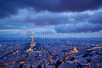 Frankreich  Paris (75) (7. und 16. Arrondissement). Erhöhte Sicht auf Dächer und Denkmäler von Paris (beleuchteter Eiffelturm und Les Invalides) in Twilight