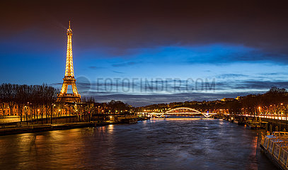 France  Paris  75007 (7th arrondissement). The Eiffel Tower illuminated at twilight with the Seine River banks and the Debilly Footbridge. Panoramic view